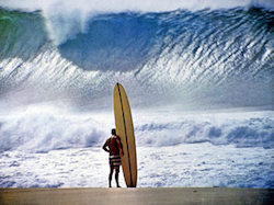 A surfer contemplates the turbulent seas, just as we must plan for turbulent markets.